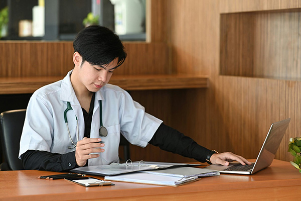 young male healthcare professional working on a laptop at his desk